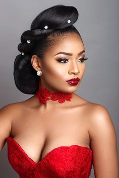 a woman wearing a red dress with her hair in a bun and earrings on top