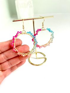 The colors of the rainbow in shimmering, sparkling hoops. I designed this colorful pair of earrings with different tones of faceted glass beads for a full spectrum effect. Earring hooks: 18K gold plated  Wire for wrapping: non-tarnish gold tone wire. Hoop: iron The earrings measure 2.8 inches in height Multicolor Faceted Earrings For Gift, Rainbow Hoop Beaded Earrings With Ear Wire, Adjustable Multicolor Crystal Earrings With Ear Wire, Multicolor Round Beads Crystal Earrings For Pierced Ears, Multicolor Wire Wrapped Round Earrings, Multicolor Crystal Earrings With Round Beads, Multicolor Round Beaded Crystal Earrings, Adjustable Multicolor Hoop Earrings, Multicolor Round Beads Crystal Earrings