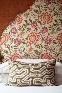 an ornate headboard and pillows on a bed