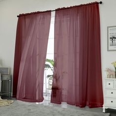 a living room with red curtains and a white dresser in front of the window,