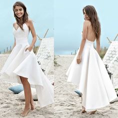 two beautiful women standing on top of a sandy beach next to clothes hanging up in the air