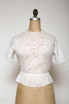 "USE COUPON CODE '25PERCENT' UPON CHECKOUT FOR YOUR DISCOUNT! Beautiful blouse semi sheer gauzy cotton.  Features lovely pink and chartreuse embroidered flowers, buttons down the back and drawstring waist. in excellent condition! may show general minor signs of age/use  Ready to wear! best fits size small: bust & waist fit 32-33\" // 84cm waist is \" // cm length from neck to hem is 19.5\" // 49.5cm * More info on our POLICIES page, here: https://www.etsy.com/shop/VeraVague/policy?ref=shopinfo_p Victorian Cotton Tops For Spring, Spring Victorian Cotton Tops, Victorian Cotton Tops For Summer, Spring Victorian Cotton Blouse, Fitted Short Sleeve Top With Yoke, Fitted Vintage Tops With Floral Embroidery, Vintage Blouse With Floral Embroidery For Daywear, Fitted Cottagecore Blouse With Floral Embroidery, Cottagecore Fitted Blouse With Floral Embroidery