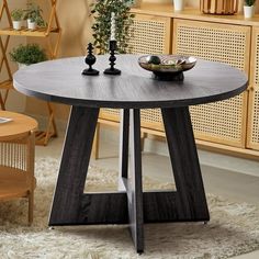 a round table with two candles on it in front of a wooden cabinet and potted plant