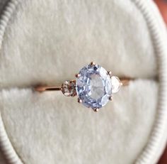 an engagement ring with a blue topaz surrounded by three white diamonds in a velvet box