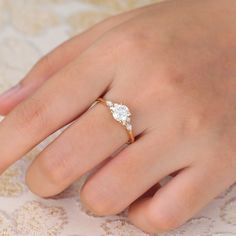 a woman's hand with a diamond ring on top of her finger and the other hand holding an engagement ring