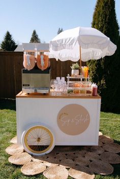 an ice cream cart is set up in the yard with umbrellas and drinks on it