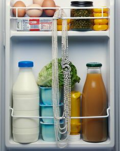 an open refrigerator filled with milk, eggs, and other foodstuffs on shelves