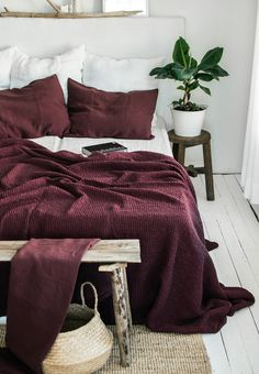 a bed covered in maroon blankets and pillows