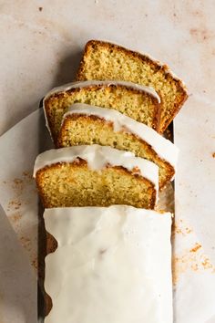 slices of cake with icing sitting on top of a white paper towel next to a loaf of bread