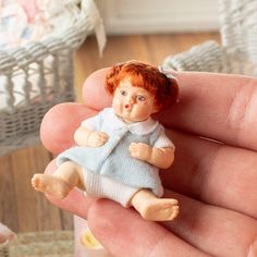 a tiny doll is sitting on someone's hand