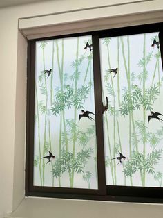 a window with birds flying over bamboo trees