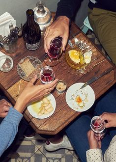 three people sitting at a table with wine and food