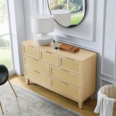 a living room with a dresser, mirror and chair