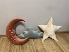 two star and moon pillows on the floor next to each other, one with a cloud in the shape of a crescent