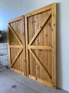 two wooden doors are open on the side of a wall in a room with a wire fence