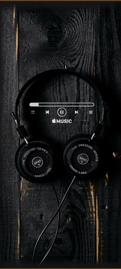 headphones on top of a wooden table with the word music written in white and black