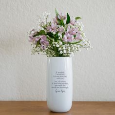 a vase filled with flowers sitting on top of a wooden table next to a wall