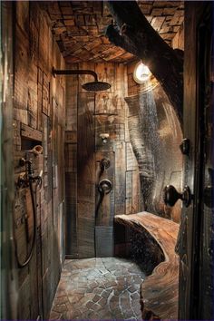 a rustic bathroom with wood paneling and stone floor, shower head, and bench