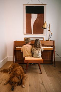 two children and a dog sitting in front of a piano