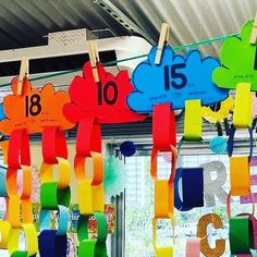 colorful paper streamers hanging from the ceiling in front of a classroom door with numbers and clouds on them