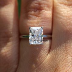 a woman's hand with a diamond ring on her finger, showing the center stone