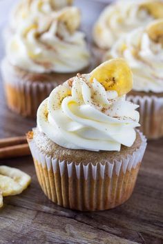 cupcakes with white frosting and banana slices on top, sitting on a wooden table