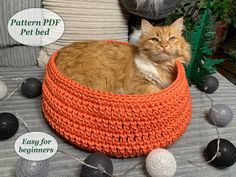 an orange and white cat sitting in a crocheted bed on a couch with balls around it