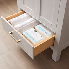 an open drawer with some cards and papers in it on top of a wooden floor