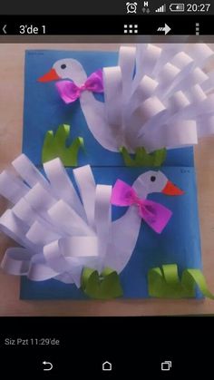 two paper birds with bows on them sitting on top of a blue piece of paper