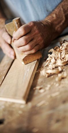 a man working with wood shavings on a wooden table