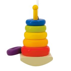 a colorful toy stacking up on top of a white surface with a yellow stick sticking out of it's center