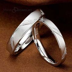 two silver wedding rings sitting on top of each other next to an orange cloth background