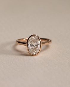 a gold ring with a white diamond in the center on a beige tablecloth background