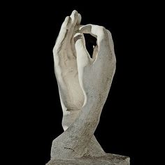 a white sculpture with hands holding something in it's palm, against a black background