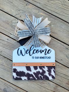 a welcome sign hanging from the side of a wooden fence with a bow on it