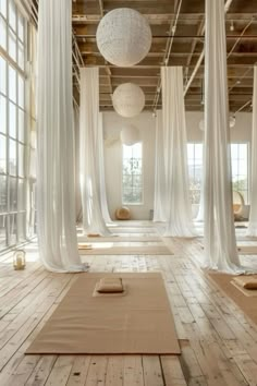 an empty room with white drapes and yoga mats