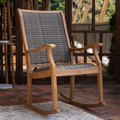 a wooden rocking chair sitting on top of a brick floor next to a patio area