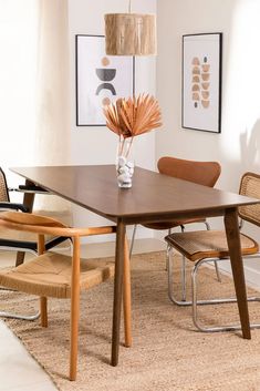 a dining room table with chairs and a vase on top of it in front of a window