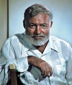 an old man with a white beard sitting in a chair and looking at the camera