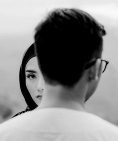 a man and woman looking at each other in black and white with mountains in the background