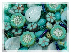 green and blue glass beads with white flowers on them are shown in close up view