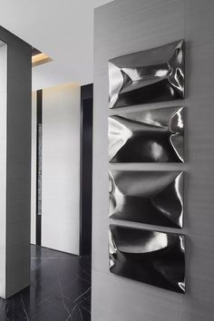 two metal sculptures on the wall next to each other in a room with black and white flooring