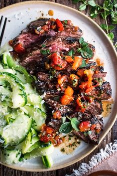 a white plate topped with meat and veggies on top of a wooden table