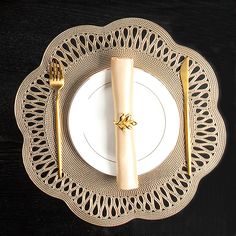 a white plate topped with a gold fork and knife next to a napkin on top of a wooden table