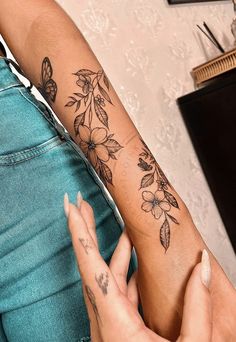 a woman with a tattoo on her arm holding onto another person's leg and the other hand