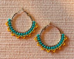 two pairs of hoop earrings with beaded details on top of a white cloth surface