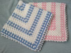 two crocheted dishcloths sitting on top of a blue and white bed