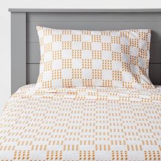 an orange and white checkered comforter set on a bed with two pillow cases