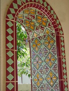 an arched window is decorated with colorful tiles and designs on the outside, along with a potted plant