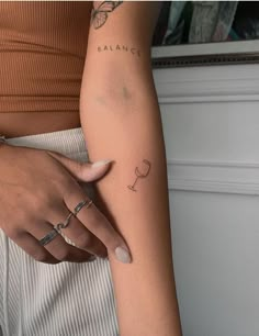 a woman's arm with a wine glass tattoo on her left arm and the word balance written in cursive writing